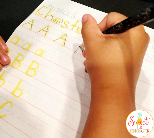 Student tracing their highlighted name with a pencil.